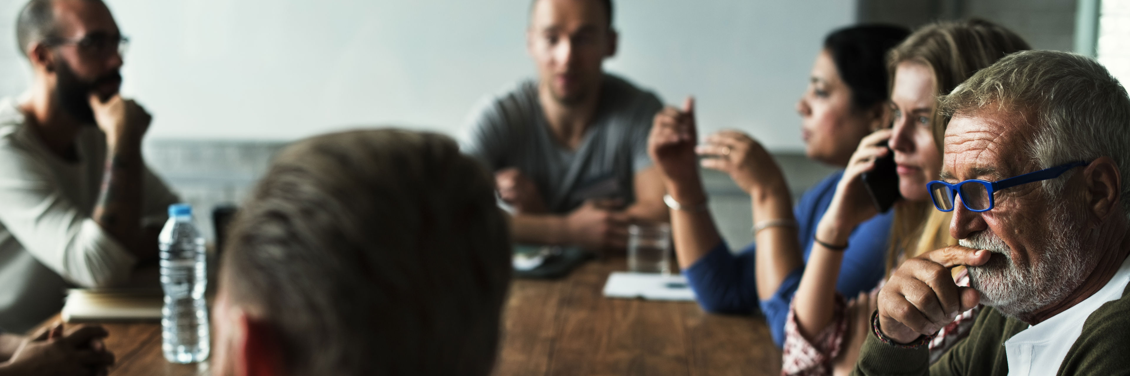 Mennesker, der sidder rundt om et bord og snakker