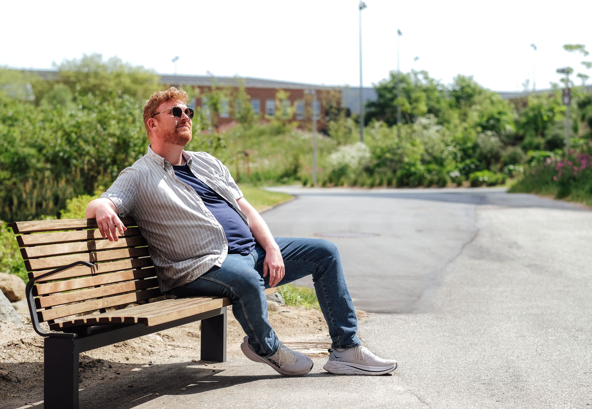 Mand, med solbriller på, sidder på bænk
