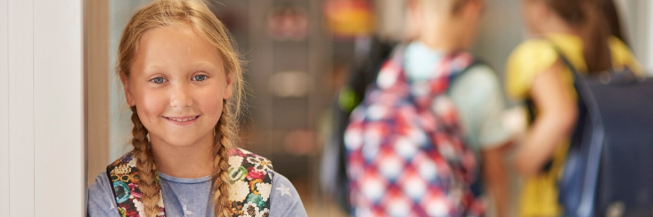 Pige med skoletaske kigger ind i kameraet. I baggrund ses tre kammerater.