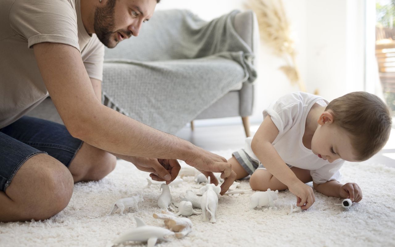 Far og barn leger med små legetøjsdyr