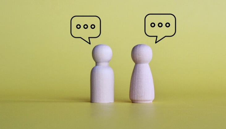 To træ brikker - en mand og en kvinde - har talebobler over deres hoveder