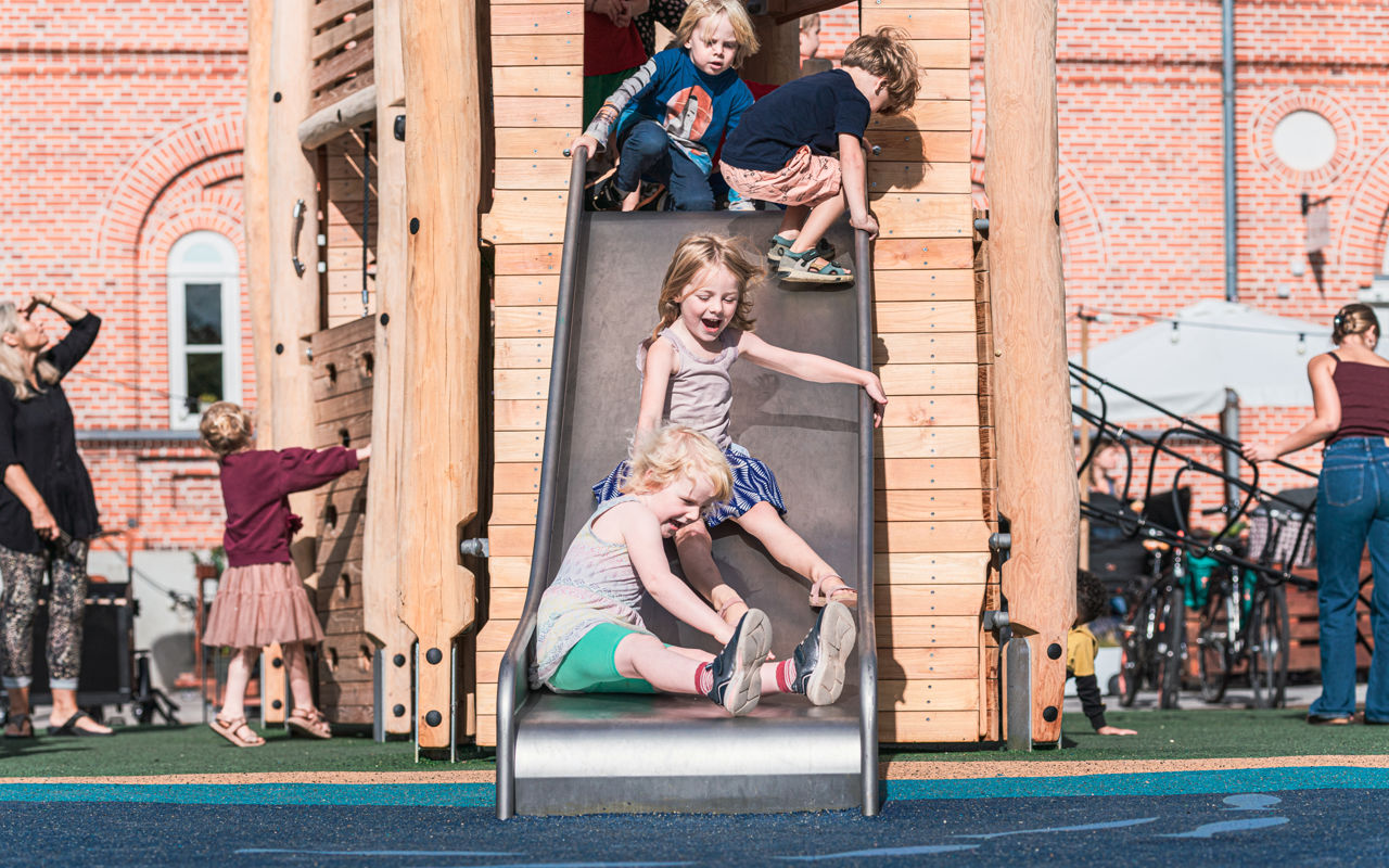 Børn rutcher ned af en rutchebane på en legeplads