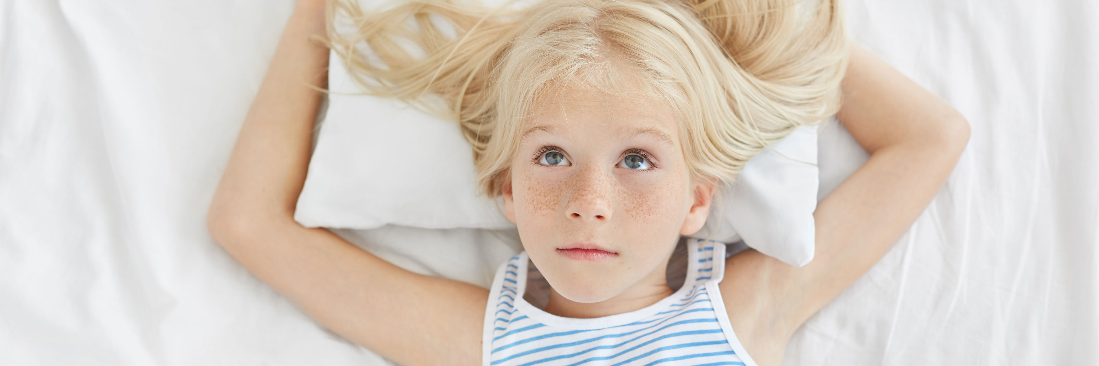 En lyshåret pige ligger i en seng