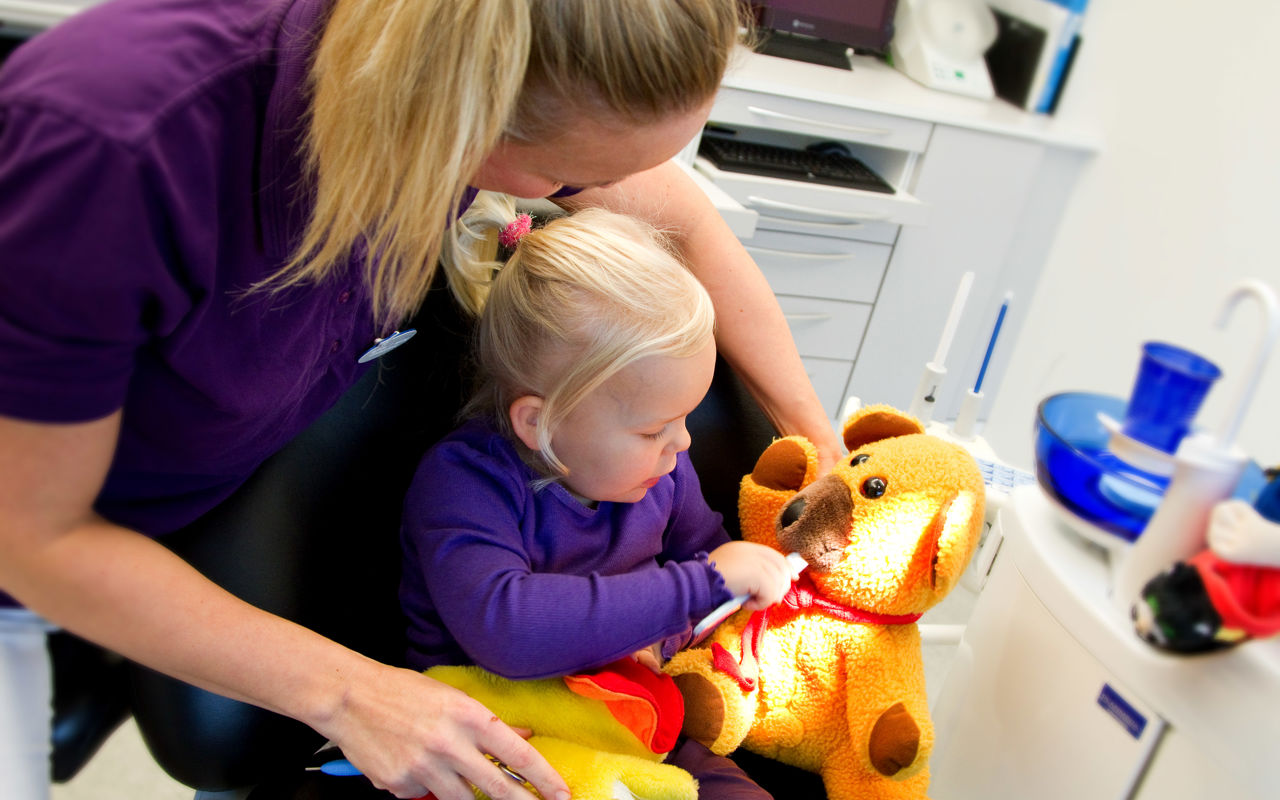 Barn ved tandlægen, børster tænder på bamse.