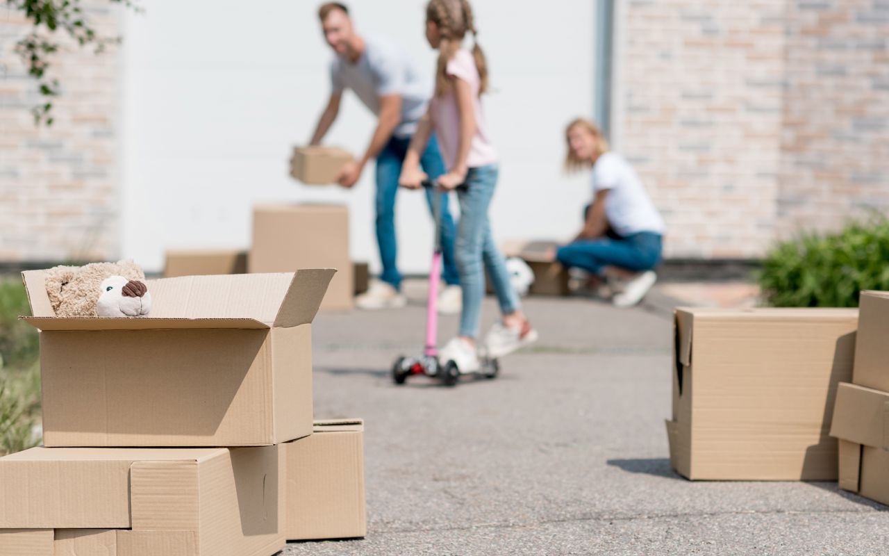 Familie med flyttekasser i indkørsel