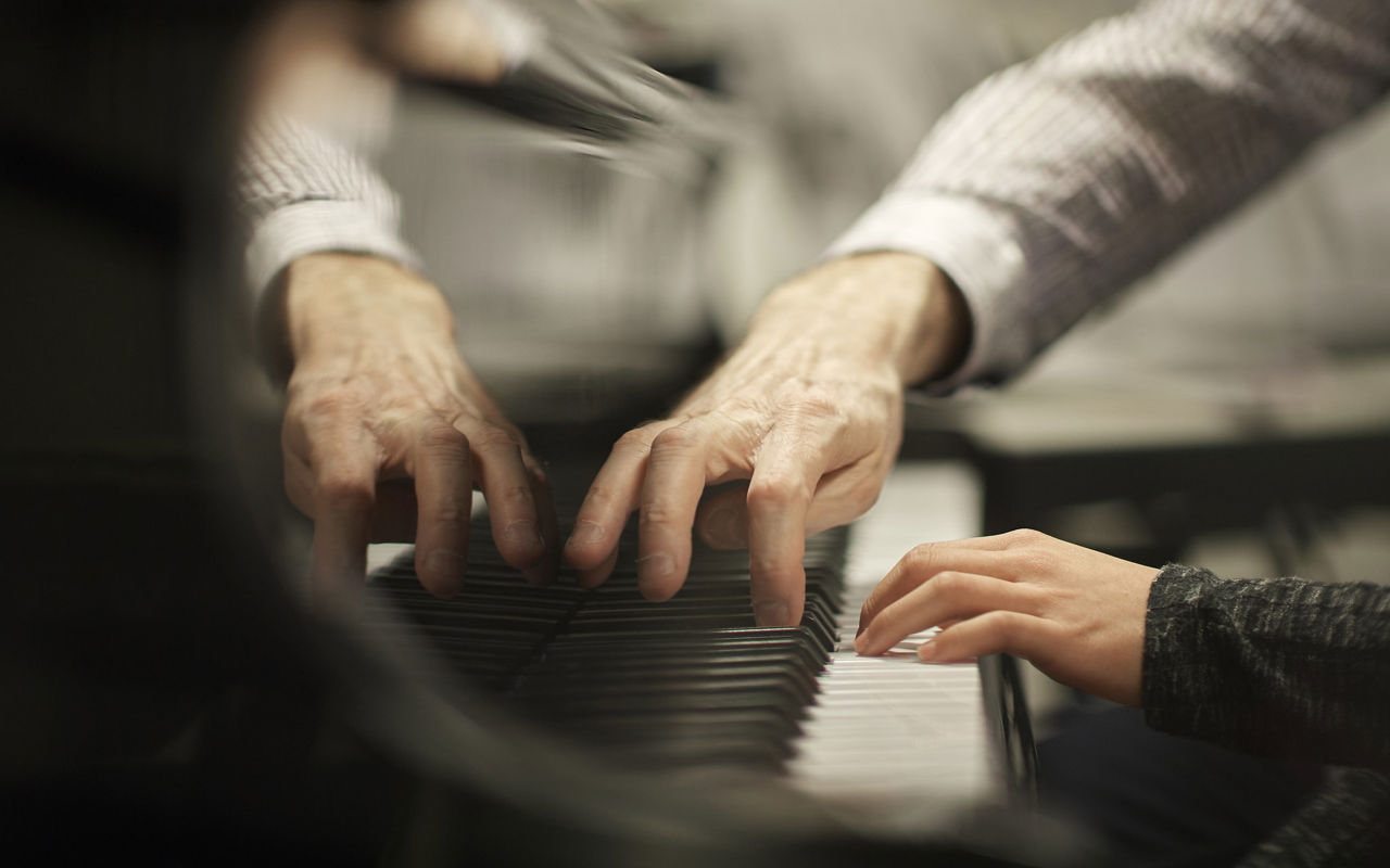 Underviser spiller klaver sammen med elev