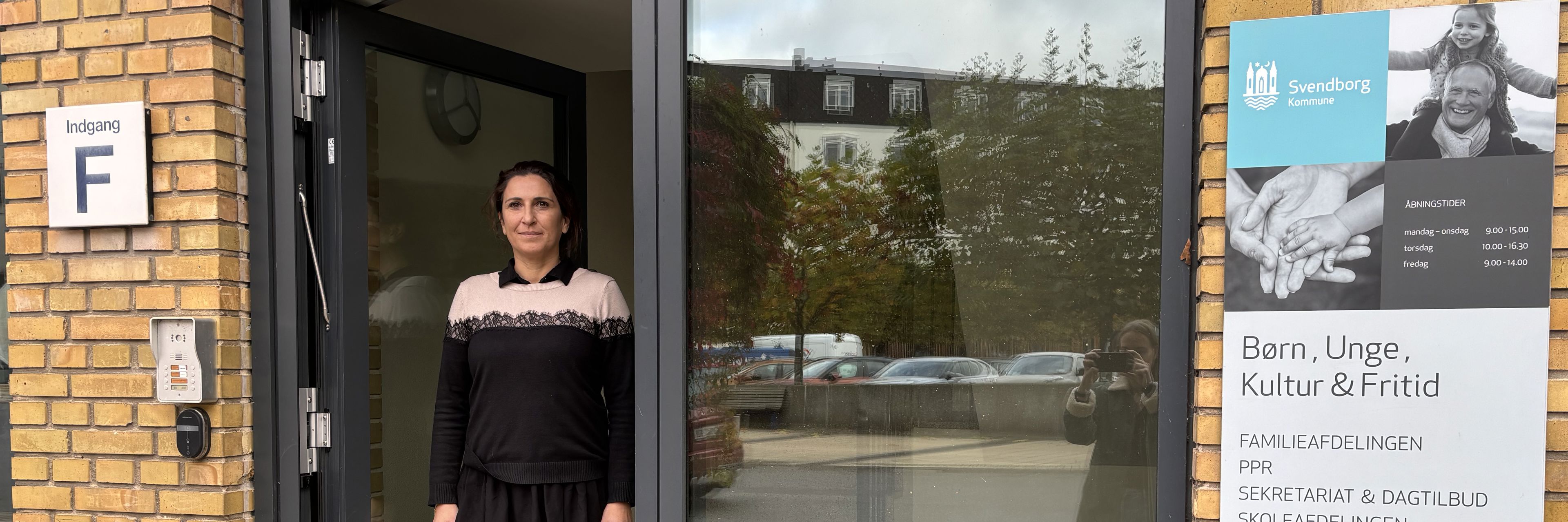 Kvinde står i indgangsdør af glas