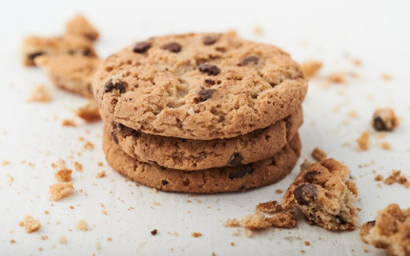 Tre småkager stablet ovenpå hinanden. Der ligger krummer rundt om dem.