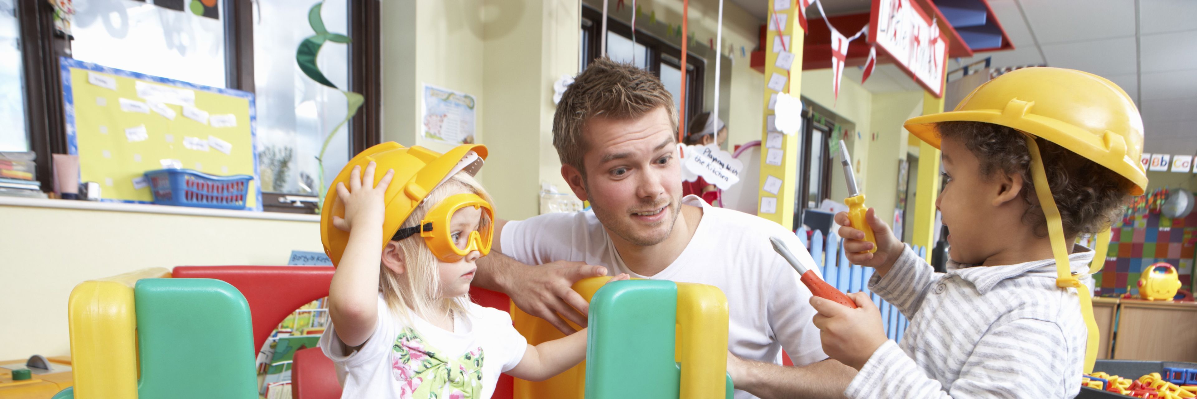 To børn som leger sammen med en mandlig pædagog